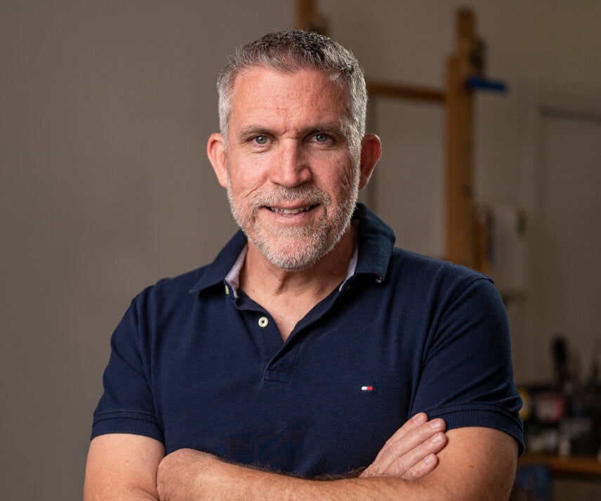 David Hart smiling and standing with arms crossed in his studio