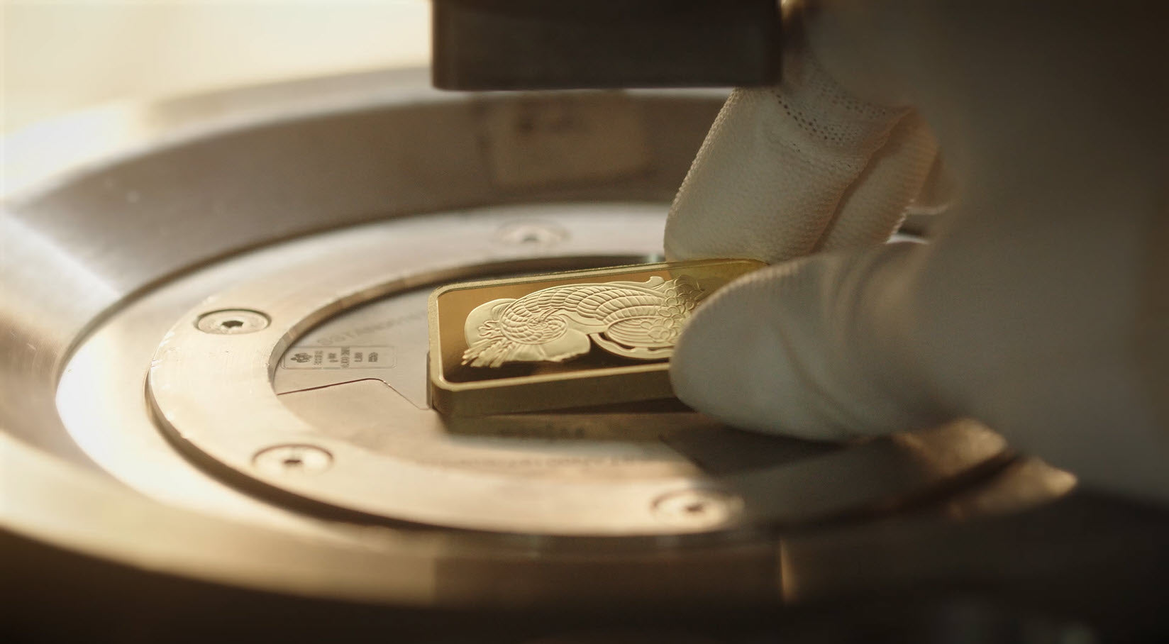 PAMP's Lady Fortuna gold bar being held by a gloved hand after being minted