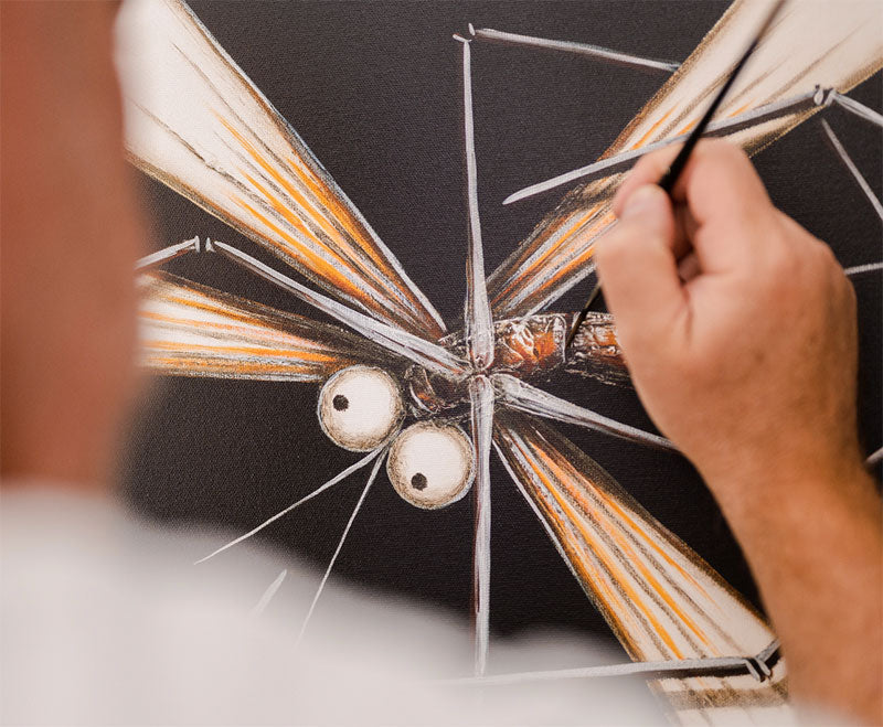 David Hart painting a dragonfly on a black canvas background