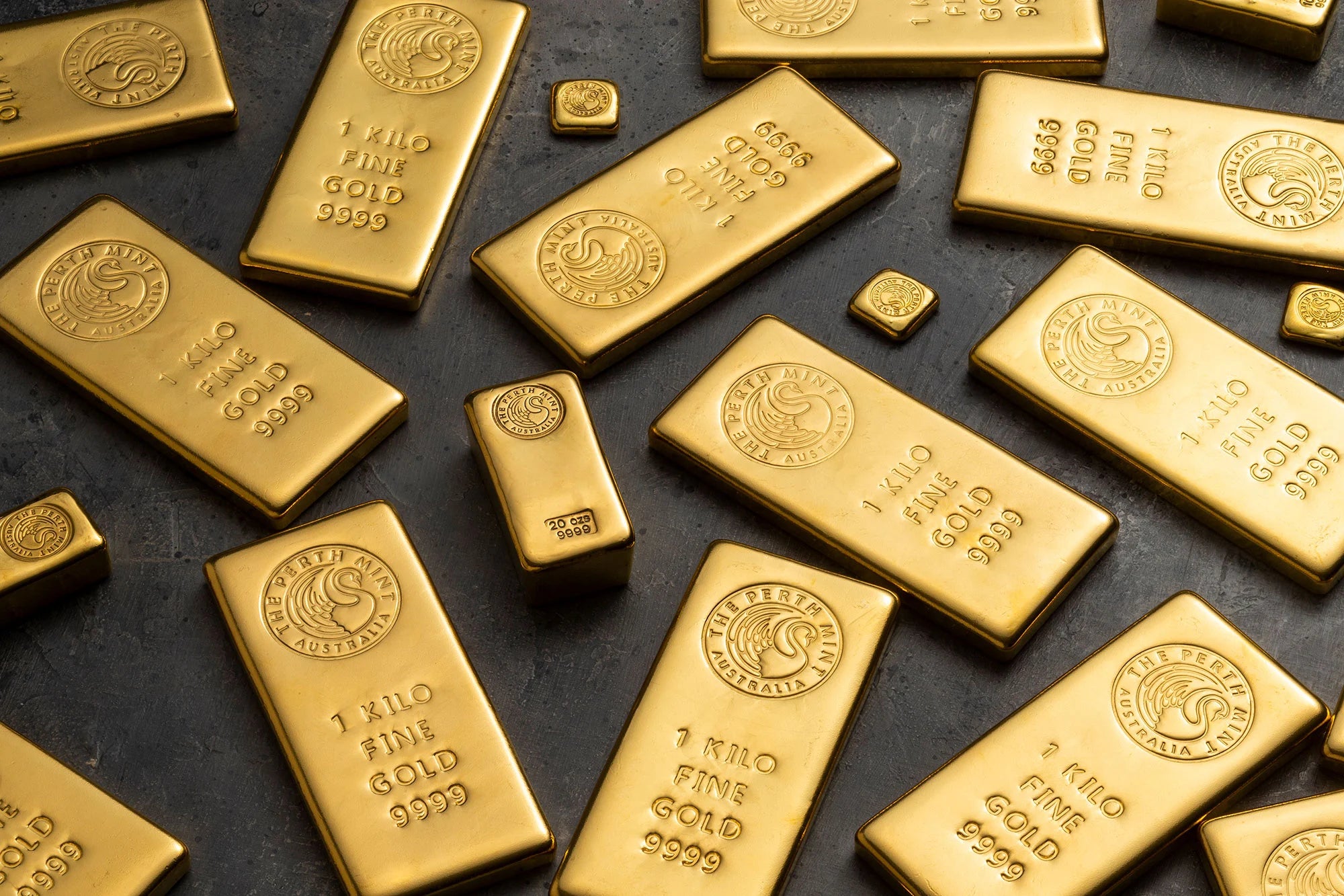 Perth Mint gold cast bars scattered on a dark surface